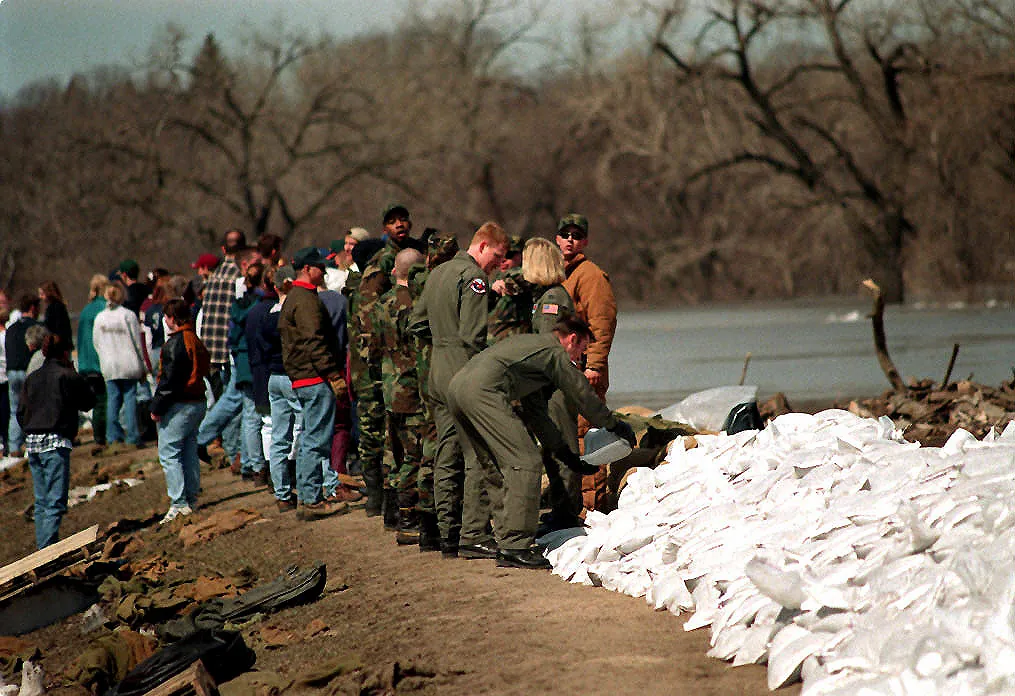 17 April 1997: U.S. Air Force personnel from Grand Forks Air Force Base pile sandbags with residents as they build a dike against the rising Red River. Photograph by Staff Sgt. Charles Morris, U.S. Air Force; public domain, via Wikimedia Commons.