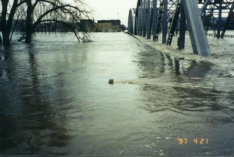 The top of a U.S. Geological Survey staff gauge set at 54.5 feet, two feet above the city levee, photographed on 21 April 1997 with the river at its height. Public domain (U.S. Geological Survey), via Wikimedia Commons.