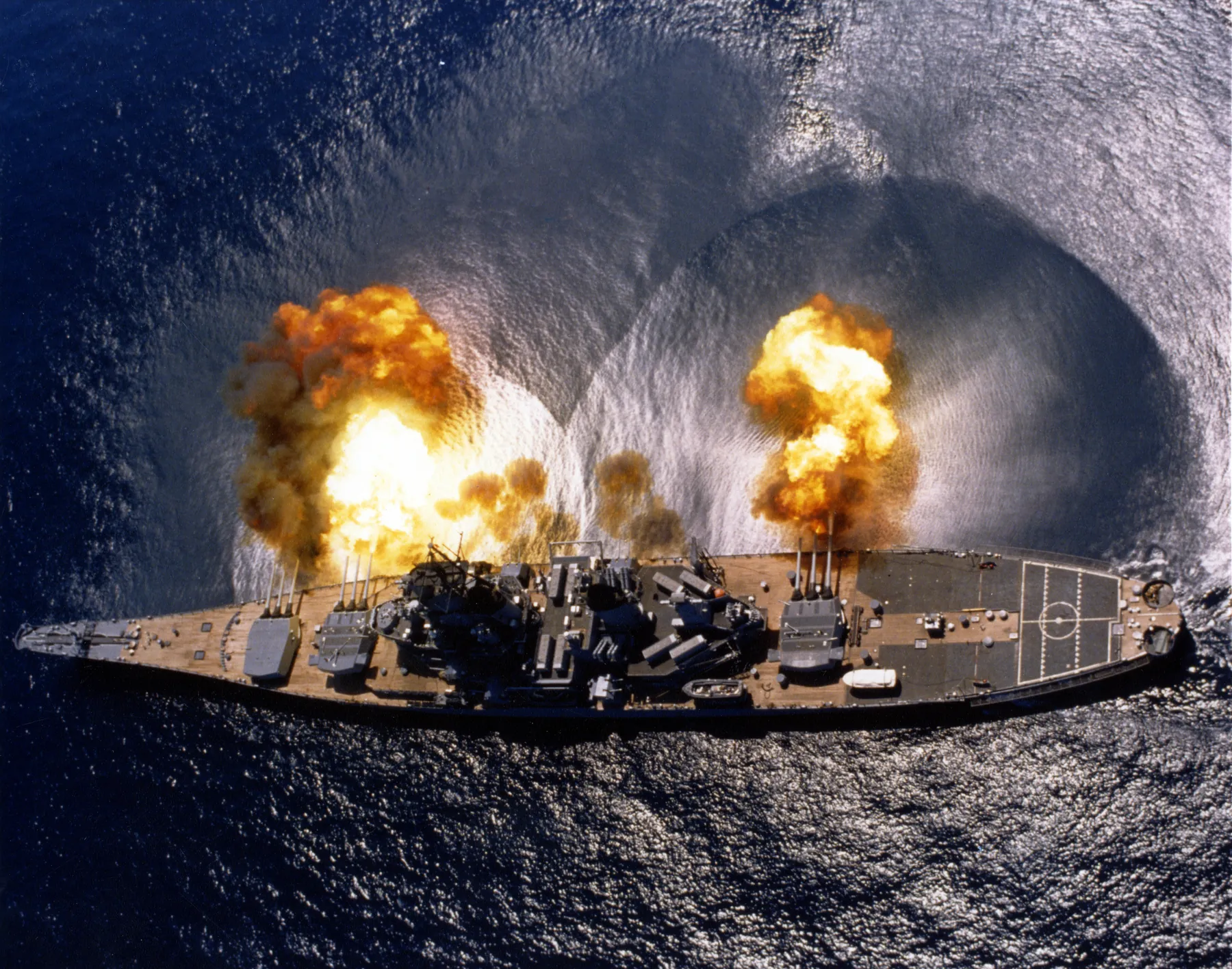 USS Iowa fires a full broadside of her nine 16-inch and six 5-inch guns near Vieques Island, Puerto Rico, 1 July 1984. The ripples on the water are the blast. US Navy photograph by PHAN J. Alan Elliott.