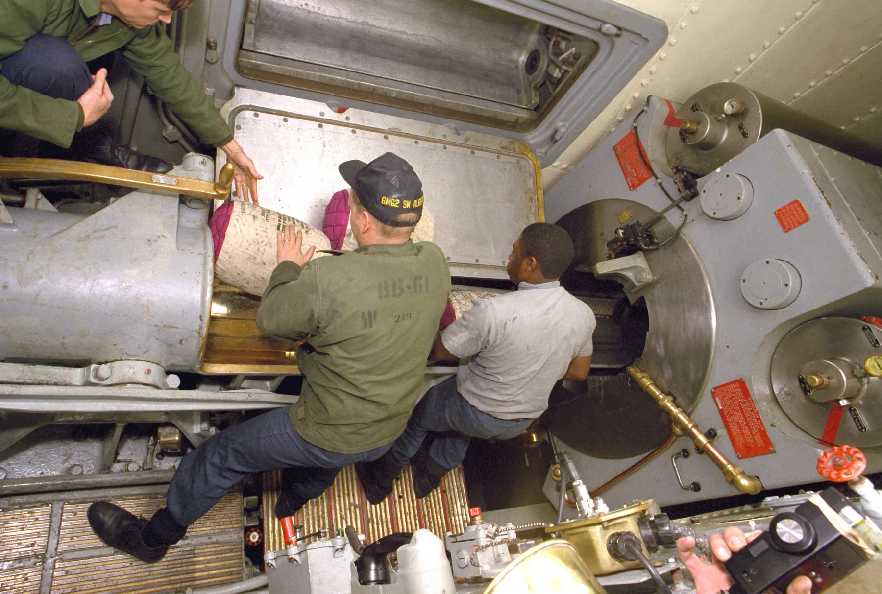 The crew of the centre gun of Iowa's No. 2 turret place powder bags on the spanning tray, 14 December 1986. The round was the 1,000th fired by her 16-inch guns since her recommissioning. US Navy photograph by PHAN William Holck.
