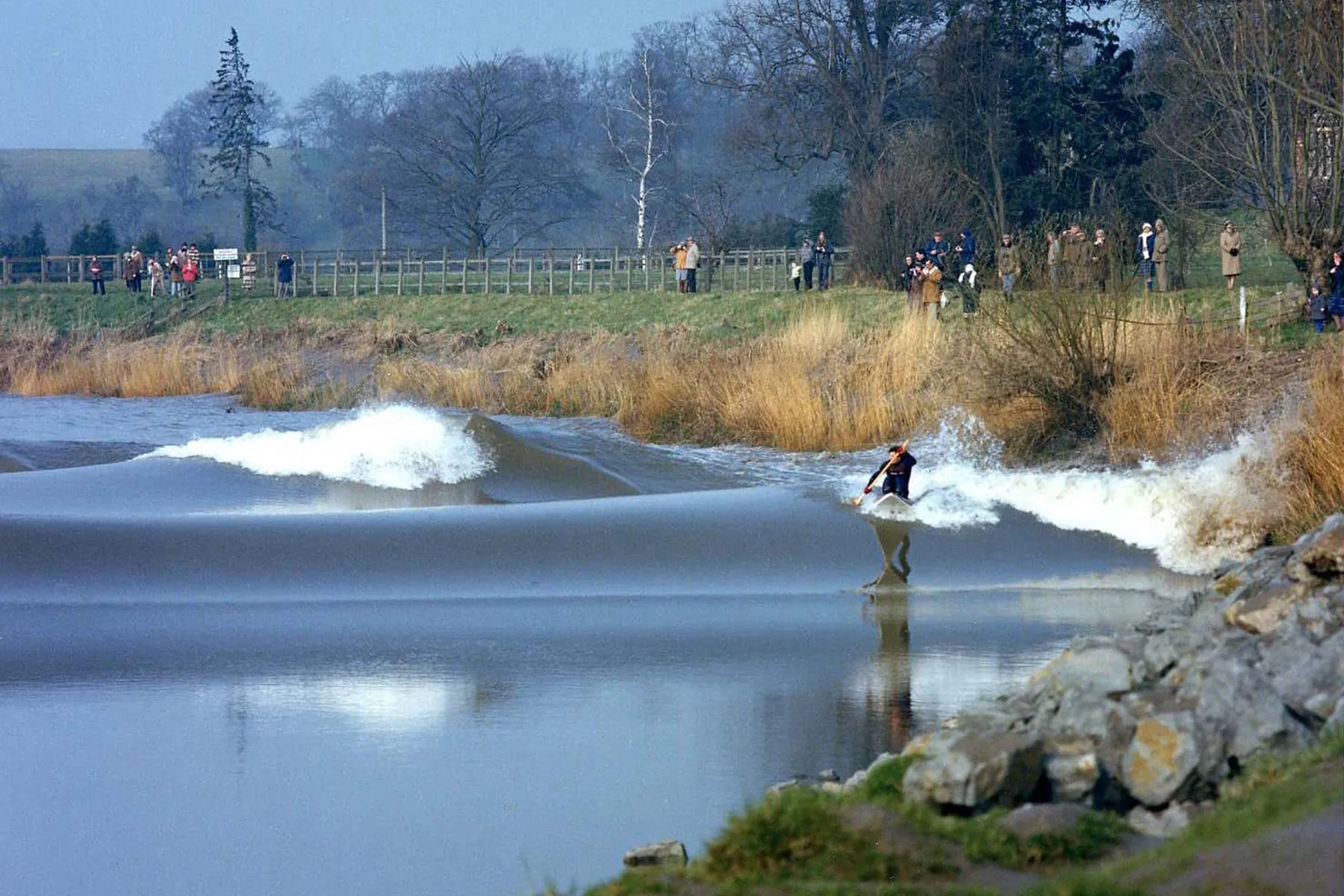 A surfer rides the Severn bore at Minsterworth, and behind the first wave a second one is rising. Photograph: Lesmalvern, CC BY-SA 4.0, via Wikimedia Commons (cropped).