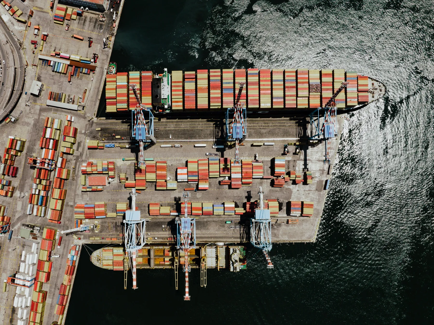 A container port in Naples. The nodes and the weights of the trade network have changed since 1930; the rule by which a country answers a tariff has not. Photograph by K, Pexels.